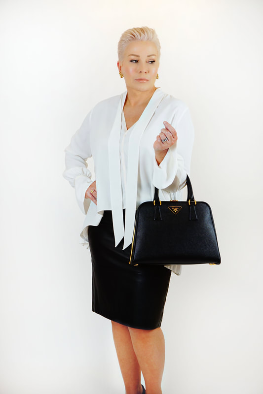 Mrs. Stafford wearing a white tie-neck blouse, black leather skirt & black pumps