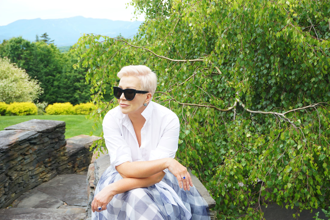 Mrs. Stafford sitting outside in a blue plaid skirt, white top & sunglasses