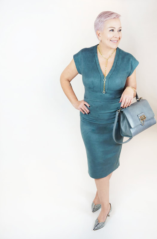 Mrs. Stafford wearing a green, suede midi dress​, a matching purse & snake skin heels