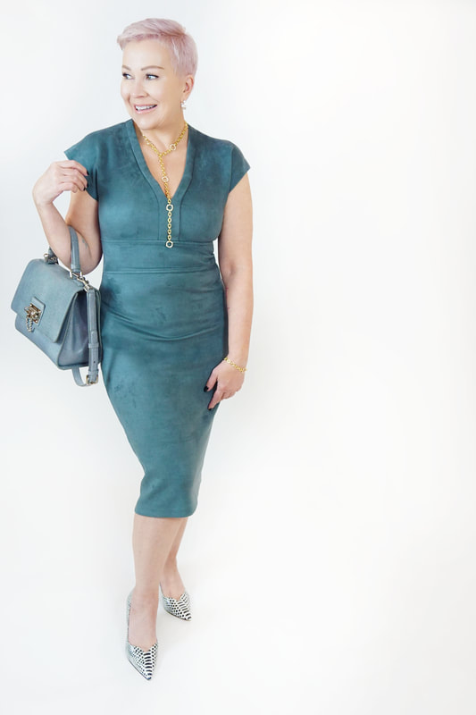 Mrs. Stafford wearing a green, suede midi dress​, a matching purse & snake skin heels