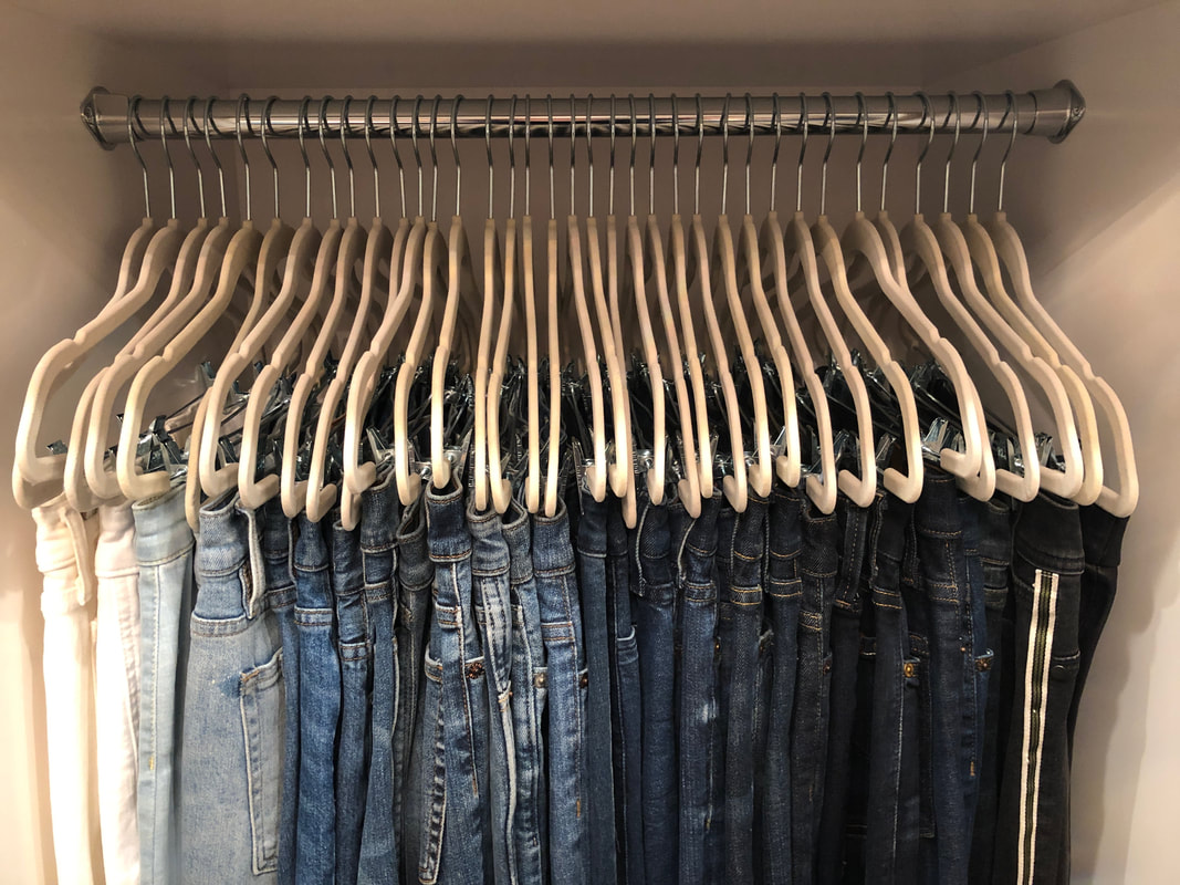 Jeans hanging in closet, organized by light to dark colors