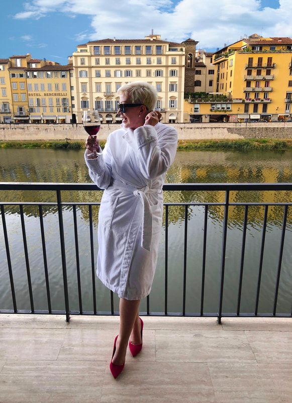 Mrs. Stafford in a robe & high heels on a balcony over River Arno in Italy